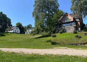 an old house on a grassy hill with houses at Reiterpension Marlie in Scharbeutz