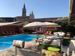 a pool with chairs and umbrellas next to a building at B&B Villa la Canonica con piscina a Padernello in Farfengo