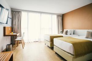 um quarto de hotel com duas camas e uma mesa em Own Montevideo em Montevidéu