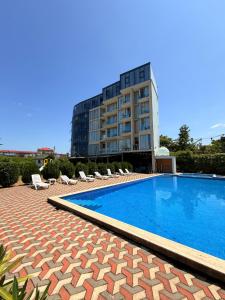 una piscina con sedie a sdraio e un edificio di Comfortium a Kobuleti