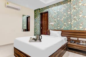 インドールにあるTownhouse Veena Nagar Bus Terminal Formerly Hotel Chandraguptaの白いベッドと花の壁紙が備わるベッドルーム1室が備わります。