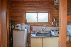 een kleine keuken met een spoelbak en een koelkast bij 神石高原ティアガルテン 