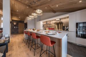 クールシュヴェルにあるChalet Rosoire Courchevel 1650 Bed&Breakfastのキッチン(赤いバースツール付きの大きな島付)