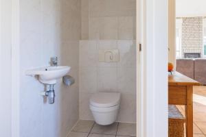 a bathroom with a toilet and a sink at Koudenburgweg 36 in Hollum +25 photos