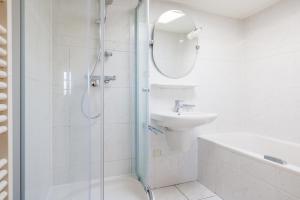 une salle de bain blanche avec une douche et un lavabo dans l'établissement Koudenburgweg 36, à Hollum 38 autres photos