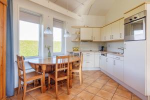 a kitchen with a wooden table and chairs and a refrigerator at Koudenburgweg 36 in Hollum