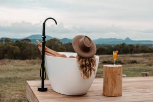a woman is sitting in a bath tub with a hat at Tiny Harry in Mudgee