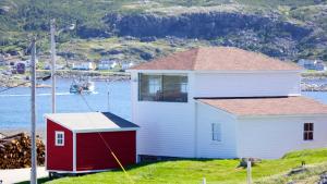 una casa y una casa pequeña junto a un cuerpo de agua en The Old Salt Box Co. - Mary's Place, en Fogo