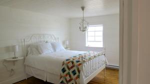 a white bedroom with a bed and a chandelier at The Old Salt Box Co. - Mary's Place in Fogo