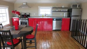 una cocina con armarios rojos y una mesa con mesa en The Old Salt Box Co. - Mary's Place, en Fogo