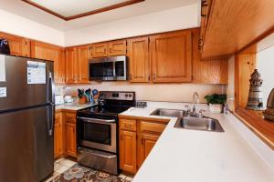 Una cocina con gabinetes de madera y un refrigerador de acero inoxidable. en AC1H - Seawind, en Nags Head 31 fotos más