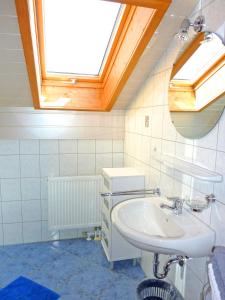 a white bathroom with a sink and a skylight at Ferienwohnungen Maurer Höhenberg in Aschau im Chiemgau