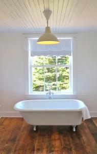 a white bath tub in a room with a window at The Old Salt Box Co. - Evelyn's Place in Herring Neck