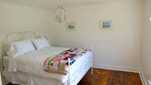 a bedroom with a white bed and a chandelier at The Old Salt Box Co. - Evelyn's Place in Herring Neck
