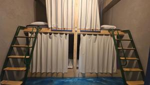a bunk bed with white curtains and two ladders at Pohang Poderosa Blue Guesthouse in Pohang