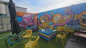a mural on the side of a building with chairs at Pohang Poderosa Blue Guesthouse in Pohang