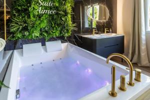 a bathroom with a bath tub and a sink at La Suite Aimée - Espace relaxant avec balnéo in Angoulême