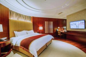 a hotel room with a large bed and a television at Shanxi World Trade Hotel in Taiyuan