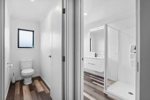 a white bathroom with a toilet and a mirror at Sunrise Hideaway - Cromwell Holiday Home in Cromwell +11 photos