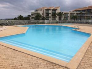 a large blue swimming pool in front of a building at Résidence Les Goélettes in Saint-Cyprien-Plage