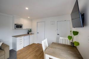 Taradale Town DistrictCabbage Tree Corner的配有白色橱柜和木桌的厨房