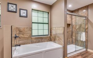 une salle de bain avec baignoire et douche en verre dans l'établissement Hidden Hollow Lodge, à Sevierville 37 autres photos