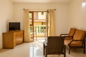 Una sala de estar con un televisor, un sofá y una silla. en Sonika's Paradise (Studio), en Candolim