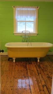 a bath tub in a green room with a window at The Old Salt Box Co. - Daisy's Place in Herring Neck