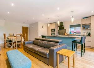 a living room with a leather couch and a kitchen at Sea Breeze in Poole