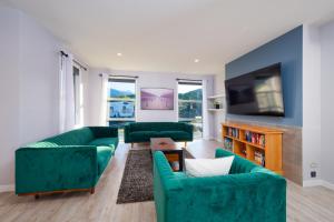 a living room with green couches and a tv at Mountain View - Kaikoura Holiday Home in Kaikoura