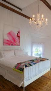 a bedroom with a large white bed with a chandelier at The Old Salt Box Co - Gertie's Place in Twillingate