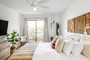 a white bedroom with a large bed with pillows at Silver Triangle Oasis with Verdant Backyard in Los Angeles