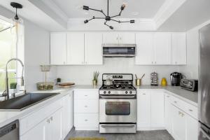 a white kitchen with a stove and a sink at Silver Triangle Oasis with Verdant Backyard in Los Angeles
