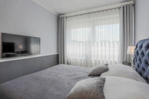 グダニスクにあるBaltic Villaのベッドルーム(ブルーヘッドボード付きのベッド1台、テレビ付)