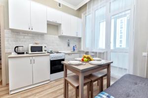 a kitchen with white cabinets and a table with fruit on it at Уютные вместительные апартаменты на Экспо in Zhezdi