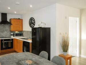 Una cocina con un refrigerador negro y una mesa. en East Lodge, en Creebridge