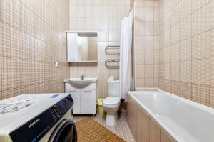 a bathroom with a tub and a toilet and a sink at Уютные вместительные апартаменты на Экспо in Zhezdi