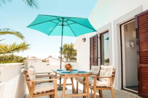 einen Tisch und Stühle mit einem blauen Regenschirm auf einer Terrasse in der Unterkunft 3 Palms in Drvenik Mali