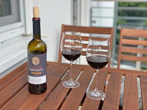 eine Flasche Wein und zwei Gläser auf einem Holztisch in der Unterkunft Villa Salus Whg 5 Auszeit - mit 2 Bädern und Balkon in Baabe