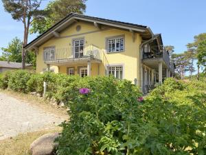 a yellow house with white windows and flowers at Haus Strandkiefer in Baabe
