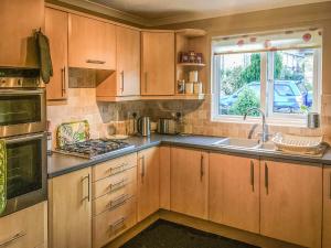 a kitchen with wooden cabinets and a sink and a window at Rothbury Cottage in Rothbury