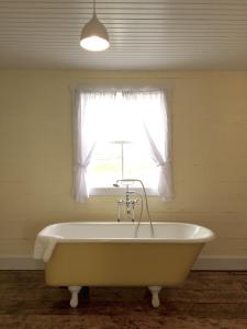 a bath tub in a room with a window at The Old Salt Box Co. - Aunt Christi's in Greenspond