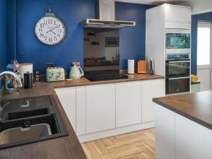 Una cocina con gabinetes blancos y un reloj en la pared. en Alscott Annexe, en Bishops Tawton
