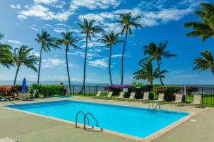 a swimming pool with palm trees and the ocean at Castle Molokai Shores in Kaunakakai