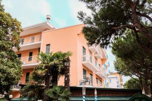 um edifício rosa com palmeiras em frente em Residence Comfort em Lido di Jesolo