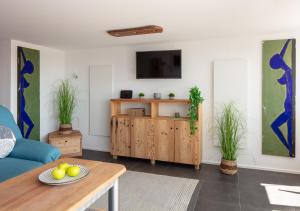 Una sala de estar con un sofá azul y un televisor. en Ferienwohnung Alpenfeuer, en Daisendorf