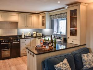 eine Küche mit weißen Schränken und einer schwarzen Arbeitsplatte in der Unterkunft The Old Workshop in Keswick