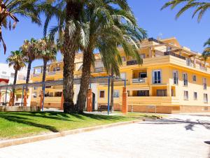 Un edificio amarillo con una palmera delante. en Primera Linea Costa Ballena con Vista al Mar, en Costa Ballena