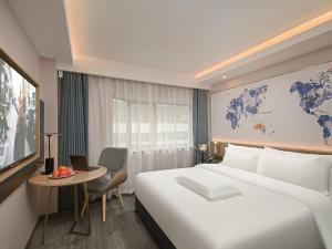 a hotel room with a large white bed and a desk at Kyriad Hotel Shenzhen Bay Port in Shenzhen