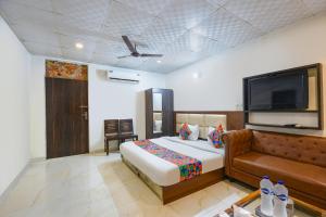 a bedroom with a bed and a couch and a flat screen tv at Via Lazeeno in Faridabad